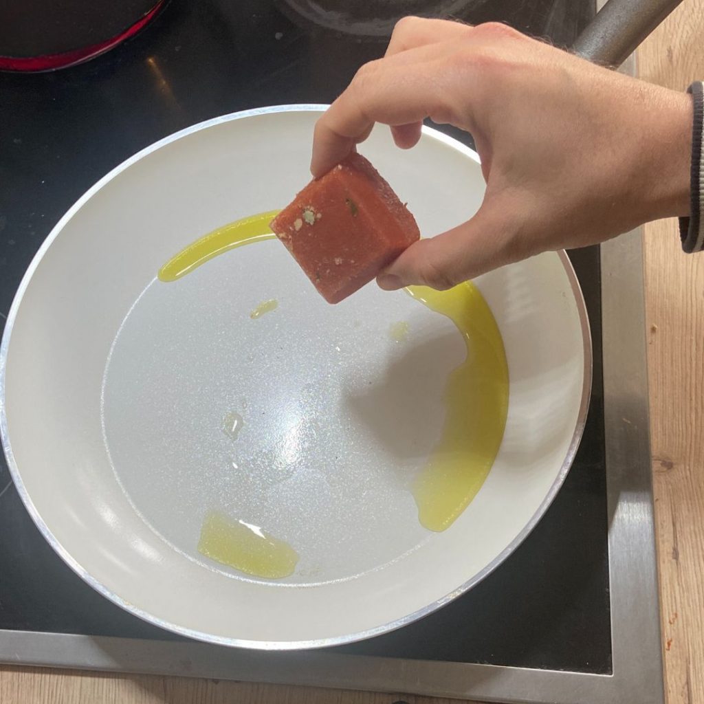 Ein Eiswürfel mit Geschmack wird in eine heiße Pfanne mit Öl gelegt